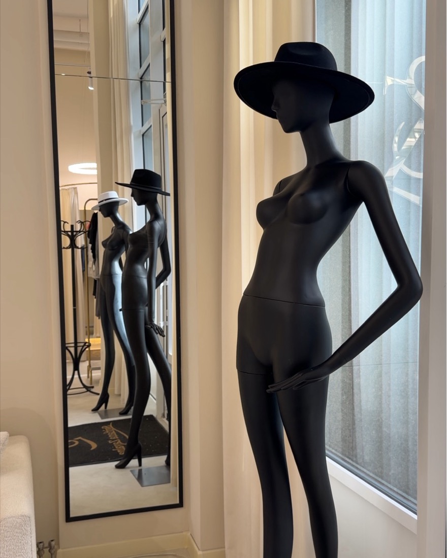 Black mannequin in a hat beside an arched mirror